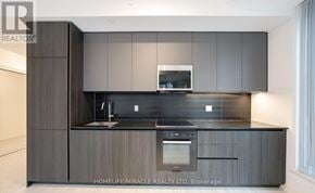 Toronto (Waterfront Communities) condo for rent - A modern kitchen with dark wood cabinets and a stainless steel oven.