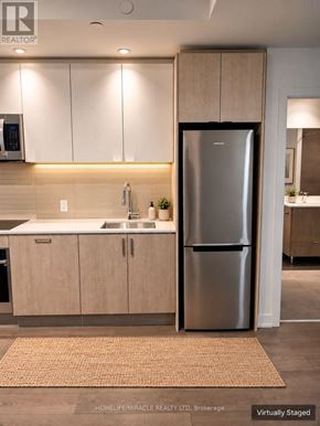 Toronto (High Park-Swansea) condo for rent - A modern kitchen with a refrigerator, sink, and cabinets.