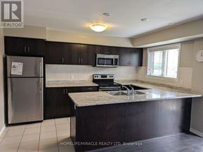 Oakville (Wm Westmount) townhouse for rent - A kitchen with a refrigerator, microwave, and stove top oven.