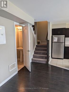 Oakville (Wm Westmount) townhouse for rent - A kitchen with a refrigerator and stairs in the background.