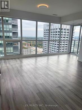 Toronto (Flemingdon Park) condo for rent - A spacious room with wooden flooring and large windows overlooking a cityscape.