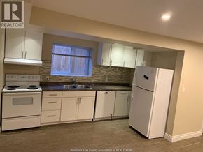 Windsor apartment for rent - A kitchen with white appliances and a stone backsplash.
