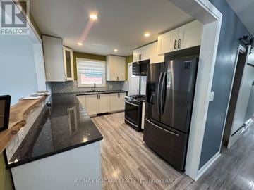 St. Catharines (Lakeport) apartment for rent - A modern kitchen with a stainless steel refrigerator and wooden cabinets.