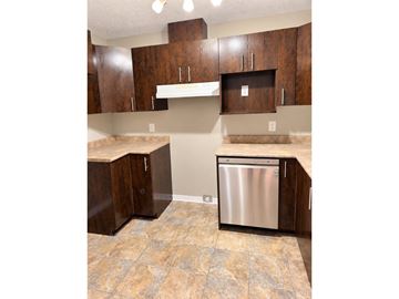 Gatineau (Aylmer) condo for rent - A kitchen with a stainless steel dishwasher and brown cabinets.