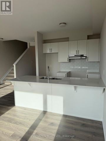 Ottawa townhouse for rent - A modern kitchen with white cabinets and a wooden floor.