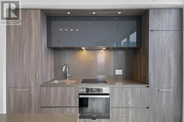 Toronto (Waterfront Communities) condo for rent - A modern kitchen with a stainless steel oven and wooden cabinets.