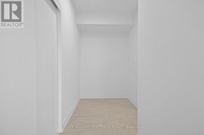 Toronto (Waterfront Communities) condo for rent - A white room with a wooden floor and a doorway leading to another room.
