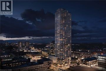 Kitchener condo for rent - A tall, illuminated building stands in the center of a cityscape at night.
