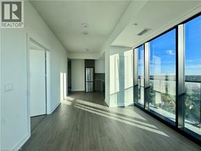 Kitchener condo for rent - A spacious room with wooden floors and large windows.