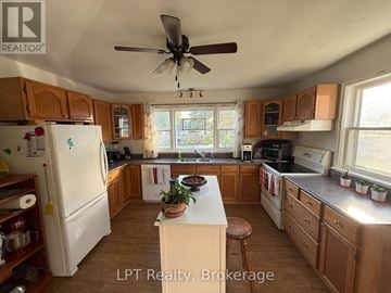Prince Edward County (Hallowell Ward) apartment for rent - A kitchen with wooden cabinets and a white refrigerator.