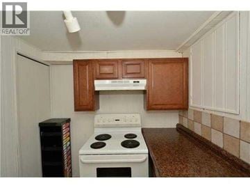 Calgary apartment for rent - A kitchen with a white stove and wooden cabinets.