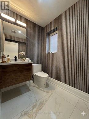Toronto (Englemount-Lawrence) apartment for rent - A bathroom with a toilet, sink, and striped wallpaper.