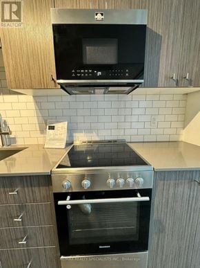 Waterloo condo for rent - A modern kitchen with a black oven and microwave above it.
