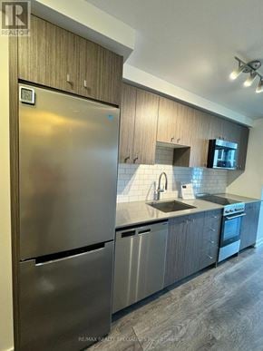 Waterloo condo for rent - A modern kitchen with a stainless steel refrigerator and wooden cabinets.
