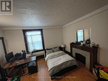 Huron-Kinloss multi-family for rent - A bedroom with a bed, desk, and fireplace.