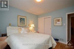 Ottawa triplex for rent - A bedroom with a bed, nightstand, and lamp.