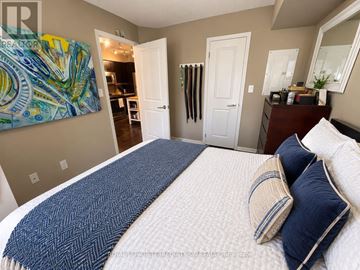 Toronto (Moss Park) condo for rent - A bedroom with a large bed and a painting on the wall.