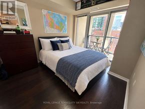 Toronto (Moss Park) condo for rent - A bedroom with a bed, a dresser, and a window overlooking a patio.