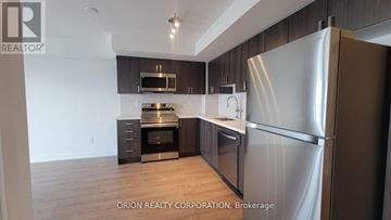 Pickering (Bay Ridges) condo for rent - A modern kitchen with a stainless steel refrigerator and wooden cabinets.