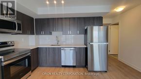 Pickering (Bay Ridges) condo for rent - A modern kitchen with dark wood cabinets and stainless steel appliances.