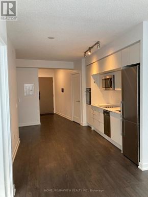 Toronto (Waterfront Communities) condo for rent - A kitchen with white walls and a wooden floor.