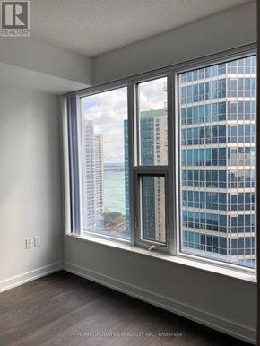 Toronto (Waterfront Communities) condo for rent - A room with a large window overlooking a cityscape.