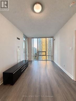 Mississauga (Fairview) condo for rent - A spacious room with a bench and a view of a cityscape through a glass door.