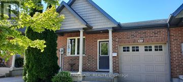 St. Catharines (Oakdale) townhouse for rent - A house with a garage and a tree in front of it.