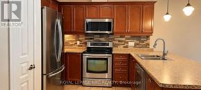 St. Catharines (Oakdale) townhouse for rent - A kitchen with a refrigerator, microwave, oven, and sink.