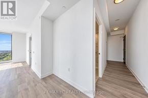 Toronto (Newtonbrook East) condo for rent - A room with white walls and wooden flooring, with a window overlooking a landscape.