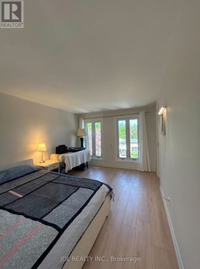 Toronto (Hillcrest Village) apartment for rent - A bedroom with a bed, a table with a lamp, and a window with curtains.