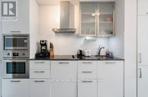 Toronto (Waterfront Communities) condo for rent - A kitchen with white cabinets and a black countertop.