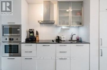 Toronto (Waterfront Communities) condo for rent - A kitchen with white cabinets and a black countertop.