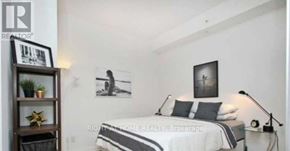 Toronto (Bendale) condo for rent - A bedroom with a bed, a nightstand, and a shelf with a plant and a star decoration.