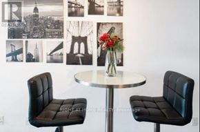 Toronto (Bendale) condo for rent - Two black chairs are placed in front of a table with a vase of flowers on it.