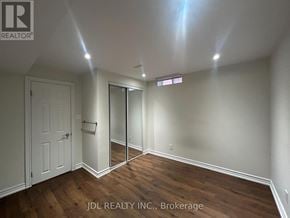 Markham (Buttonville) apartment for rent - A room with wooden floors and white walls, with a door and a mirror on the wall.