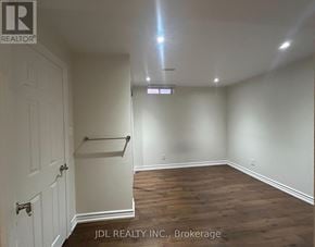 Markham (Buttonville) apartment for rent - A room with wooden flooring and white walls, with a door on the left and a shelf on the right.
