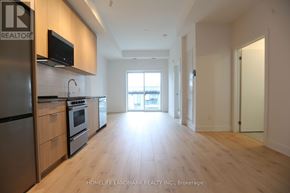 Oakville (Jm Joshua Meadows) condo for rent - A kitchen with wooden floors and a refrigerator with a microwave on top.