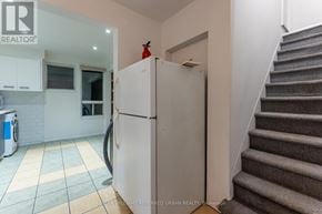 Toronto (Dovercourt-Wallace Emerson-Junction) triplex for rent - A kitchen with a white fridge and a staircase.