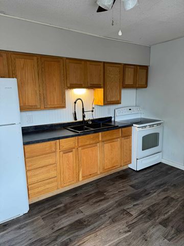 Mccomb apartment for rent - A kitchen with wooden cabinets and white appliances.