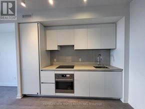 Mississauga (City Centre) condo for rent - A kitchen with white cabinets and appliances in a real estate listing.