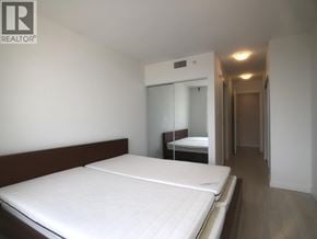 Richmond apartment for rent - A bedroom with a bed, a mirror, and a wardrobe.