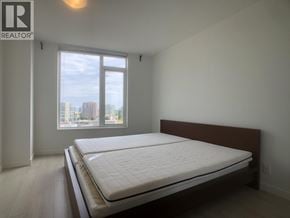 Richmond apartment for rent - A bedroom with a large bed and a window overlooking a cityscape.