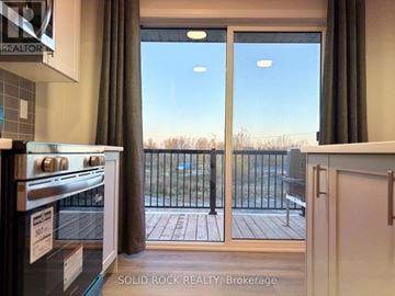 Ottawa townhouse for rent - A kitchen with a stove top oven and a sliding glass door leading to a balcony.