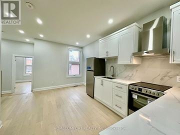 Toronto (Weston-Pellam Park) duplex for rent - A kitchen with white cabinets and a black fridge.