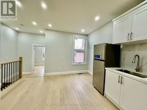 Toronto (Weston-Pellam Park) duplex for rent - A kitchen with white cabinets and a black refrigerator.