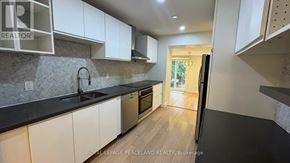Toronto (Wexford-Maryvale) apartment for rent - A kitchen with white cabinets and a black countertop.