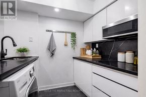 Toronto (Willowdale East) townhouse for rent - A modern kitchen with white cabinets and black countertops.