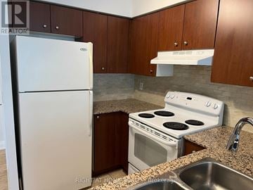 Markham (Unionville) condo for rent - A kitchen with a white fridge, white stove and brown cabinets.