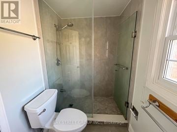 Markham (Markham Village) apartment for rent - A white toilet sits in a small bathroom with a glass shower door.